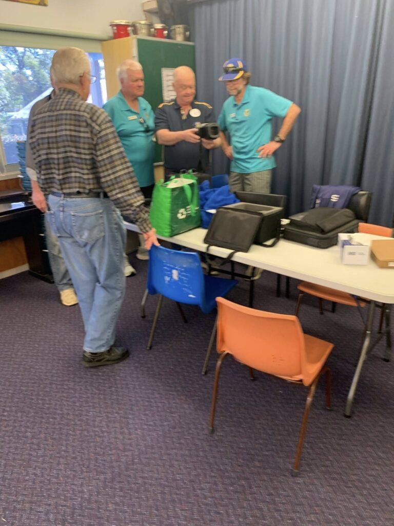 A group of Lions members standing by a desk with eye diagnostic equipment
